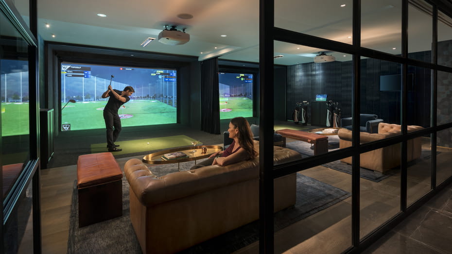 a couple enjoys a game of virtual golf at the Topgolf facility in the Four Seasons Hotel in Houston