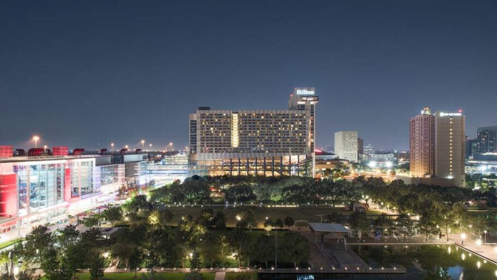 the Hilton Americas - Houston hotel is lit up at night in front of the Toyota Center - home of the NBA Houston Rockets