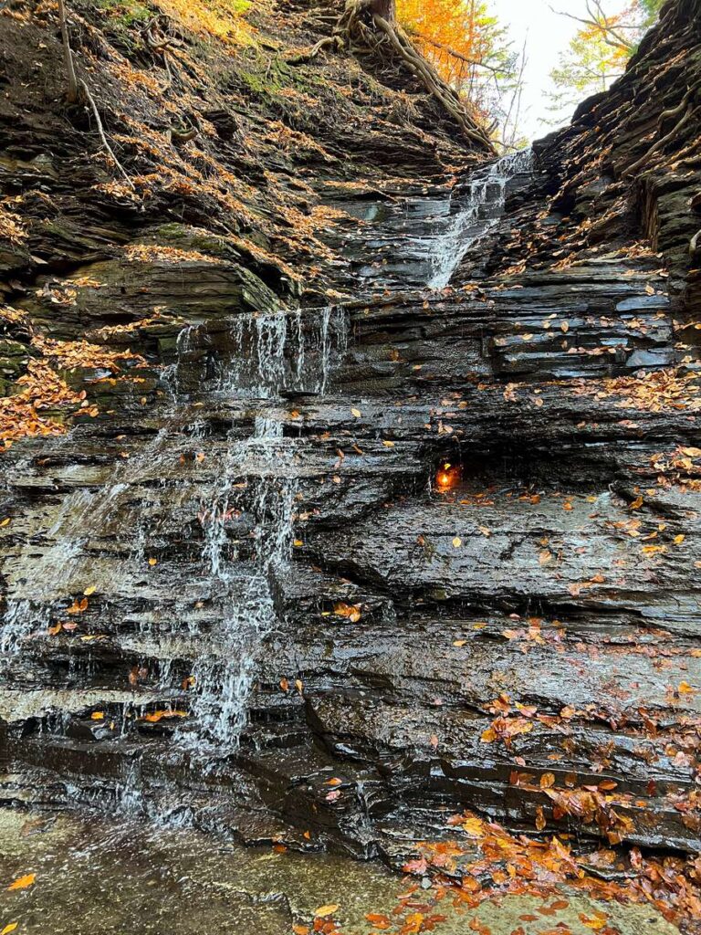 an eternal flame burns next to a waterfall in Chestnut Ridge State Park, NY
