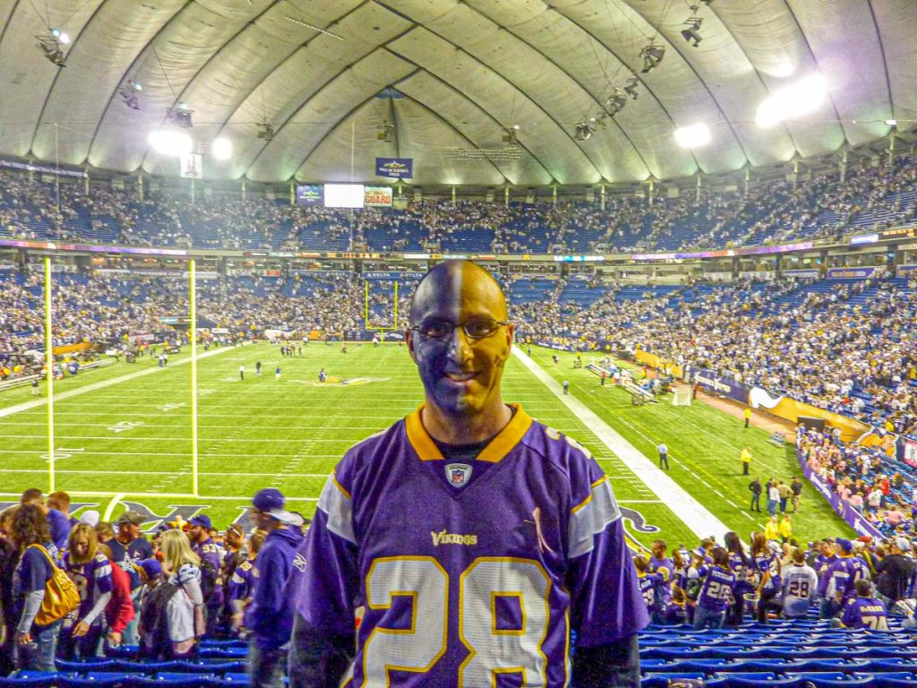 Dan Brewer, of the Ultimate Sports Road Trip website, has his face painted Vikings colors before a game at the old Metrodome.